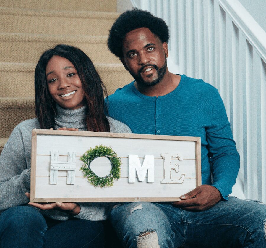 Man and woman displaying home sign