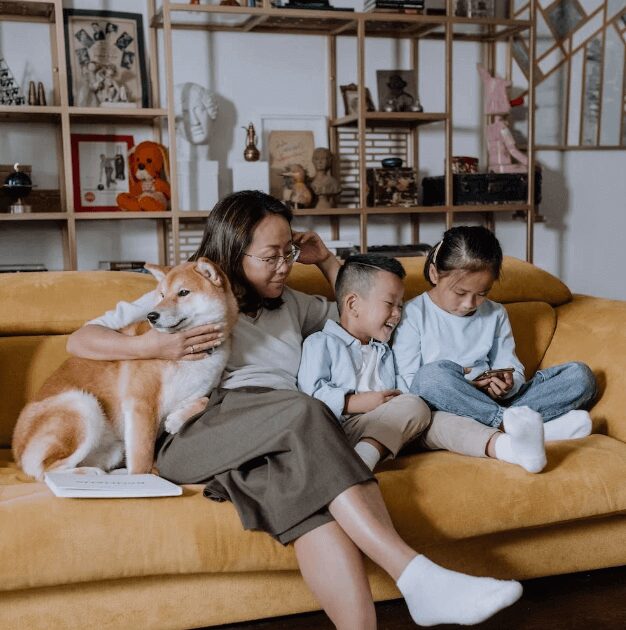 Family relaxing on yellow sofa with dog