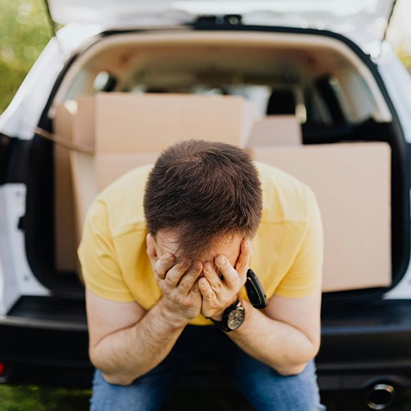 Frustrated individual sitting by vehicle