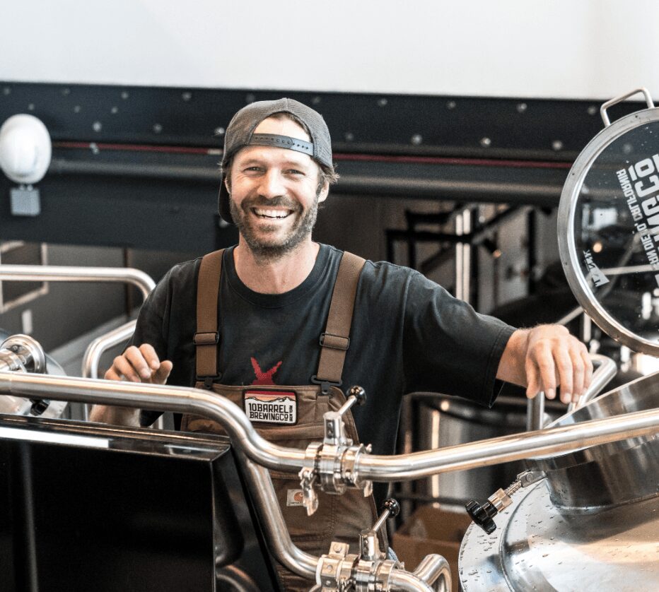 Brewer smiling near brewing equipment