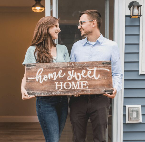 Happy pair with wooden welcome sign