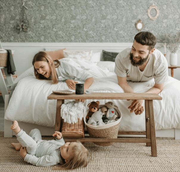 Parents laughing with toddler in bedroom