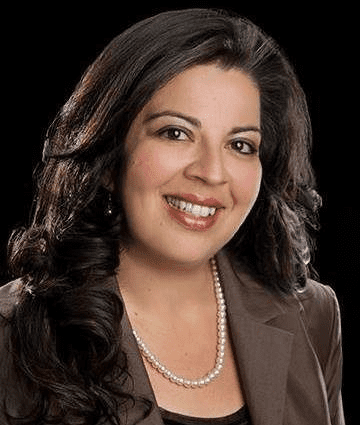 Professional woman with dark hair and a warm smile wearing a pearl necklace.